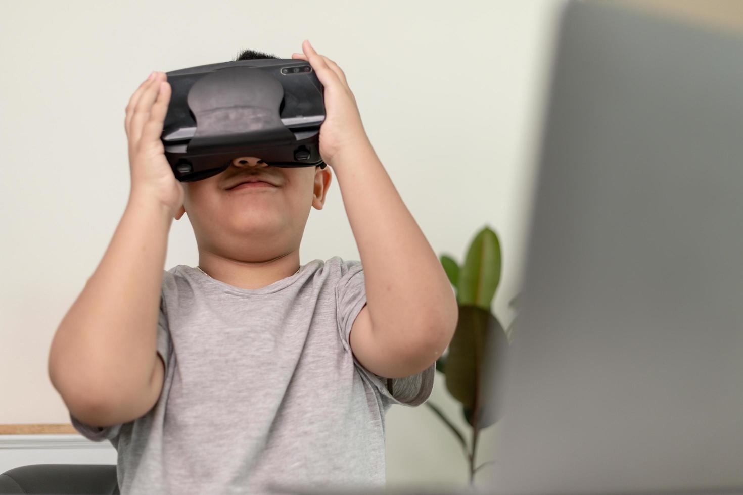 Asian Little boy with VR glasses studying sciences at home,curious student wears a virtual reality headset to study science home online study futuristic lifestyle learning photo