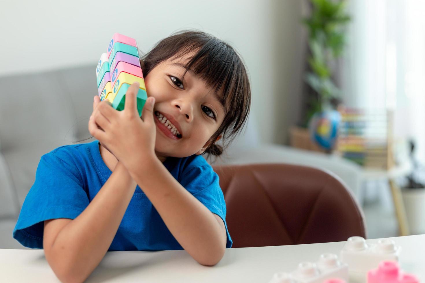 Adorable little girl playing toy blocks in a bright room photo