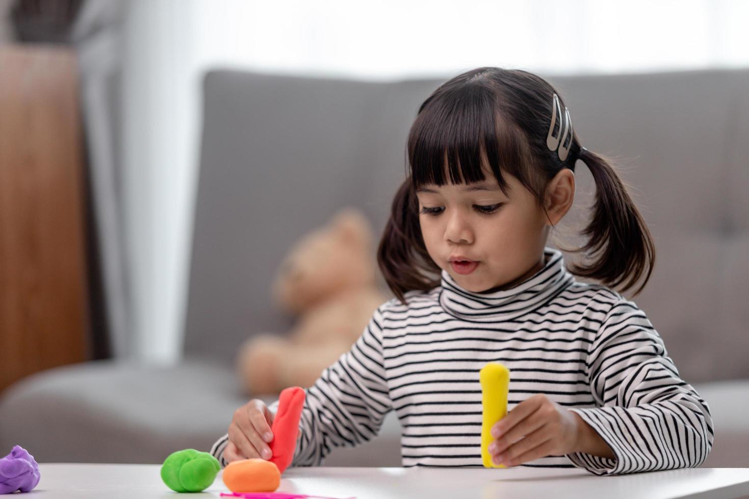 The little girl is learning to use colorful play dough in a well lit room photo