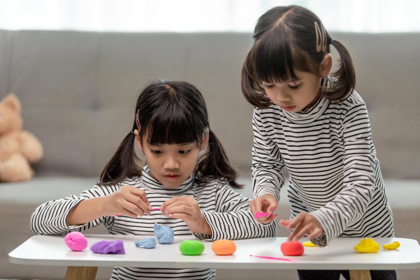 The little girl is learning to use colorful play dough in a well lit room photo