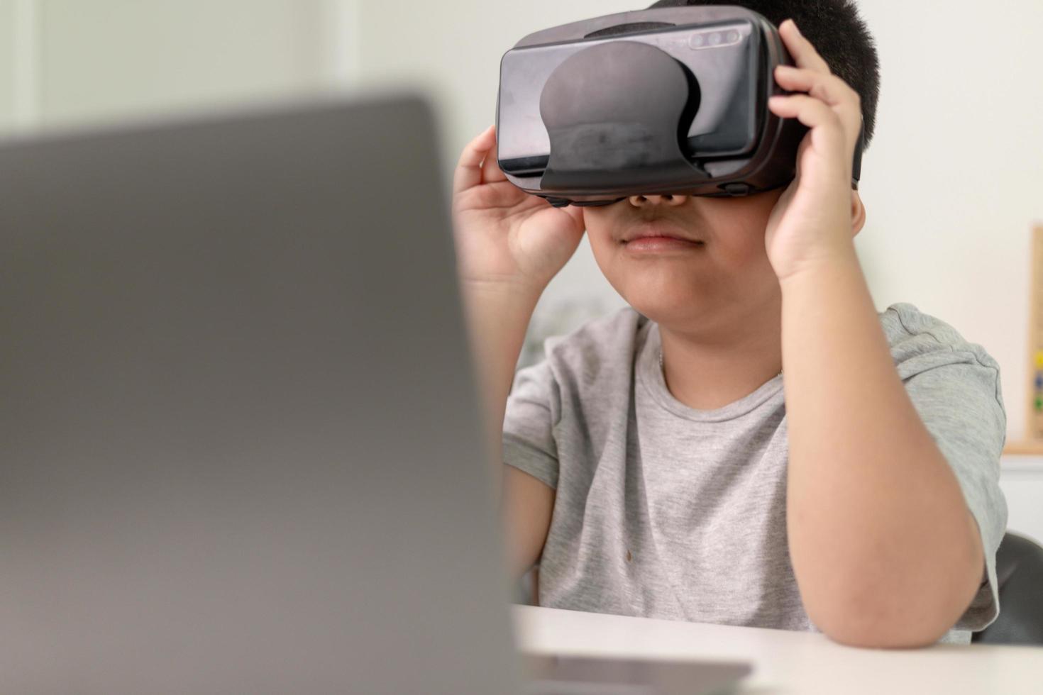 Asian Little boy with VR glasses studying sciences at home,curious student wears a virtual reality headset to study science home online study futuristic lifestyle learning photo