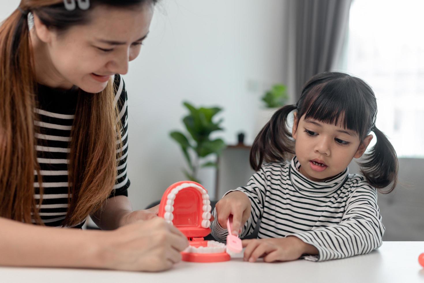 mother teaching daughter child teeth brushing at home photo