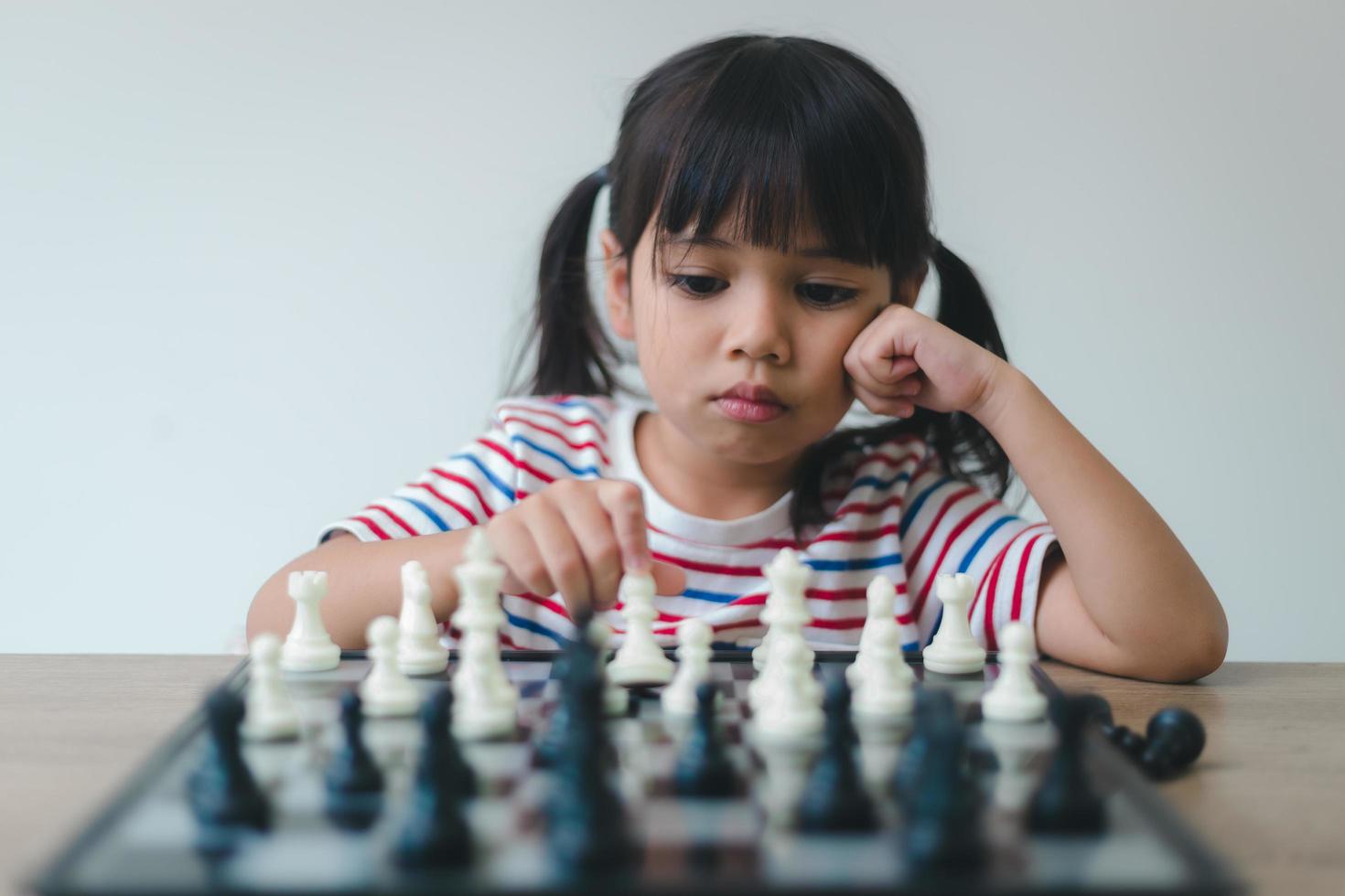 niña asiática jugando al ajedrez en casa.un juego de ajedrez foto