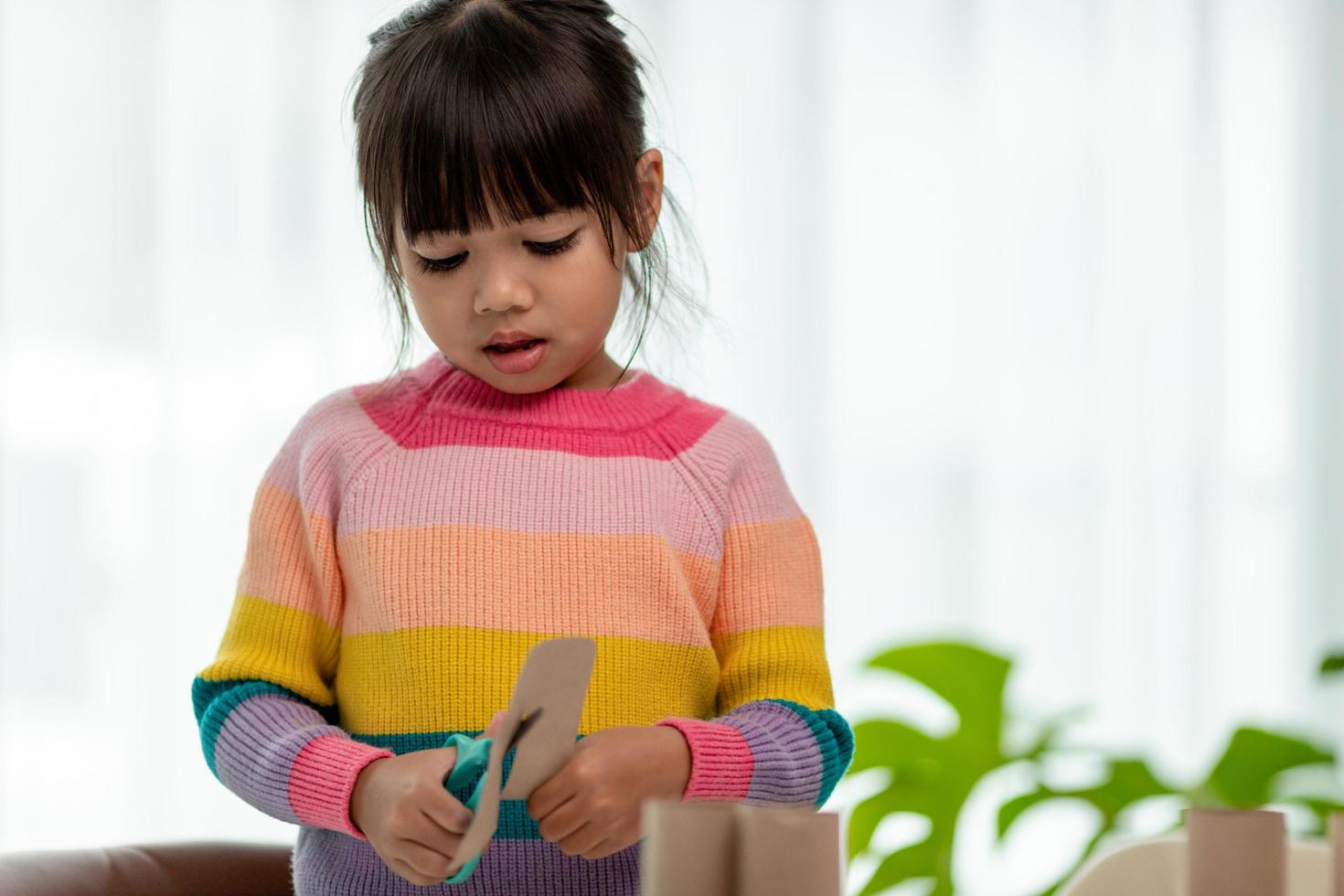 Portrait of a little asian girl cutting a paper in activities on DIY class at School.Scissors cut paper. photo