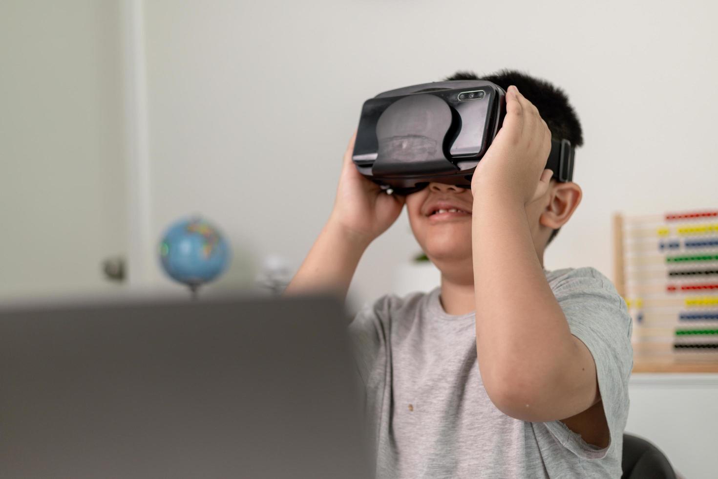 Asian Little boy with VR glasses studying sciences at home,curious student wears a virtual reality headset to study science home online study futuristic lifestyle learning photo