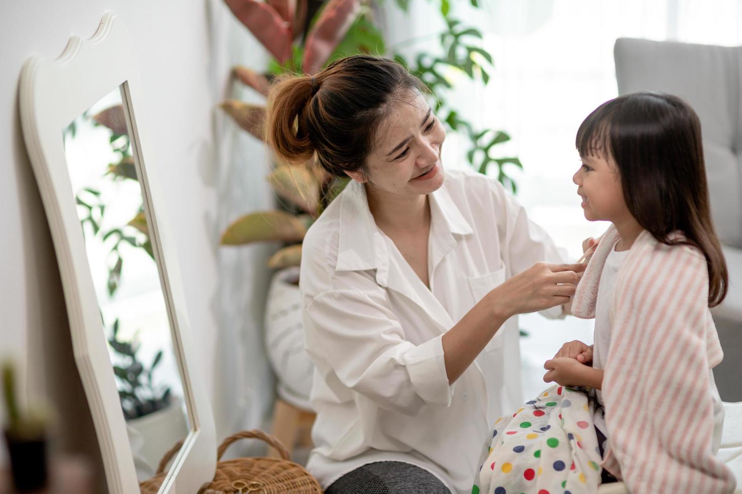 Asian Mother cutting hair to her daughter in living room at home while stay at home safe from Covid-19 Coronavirus during lockdown. Self-quarantine and social distancing concept. photo