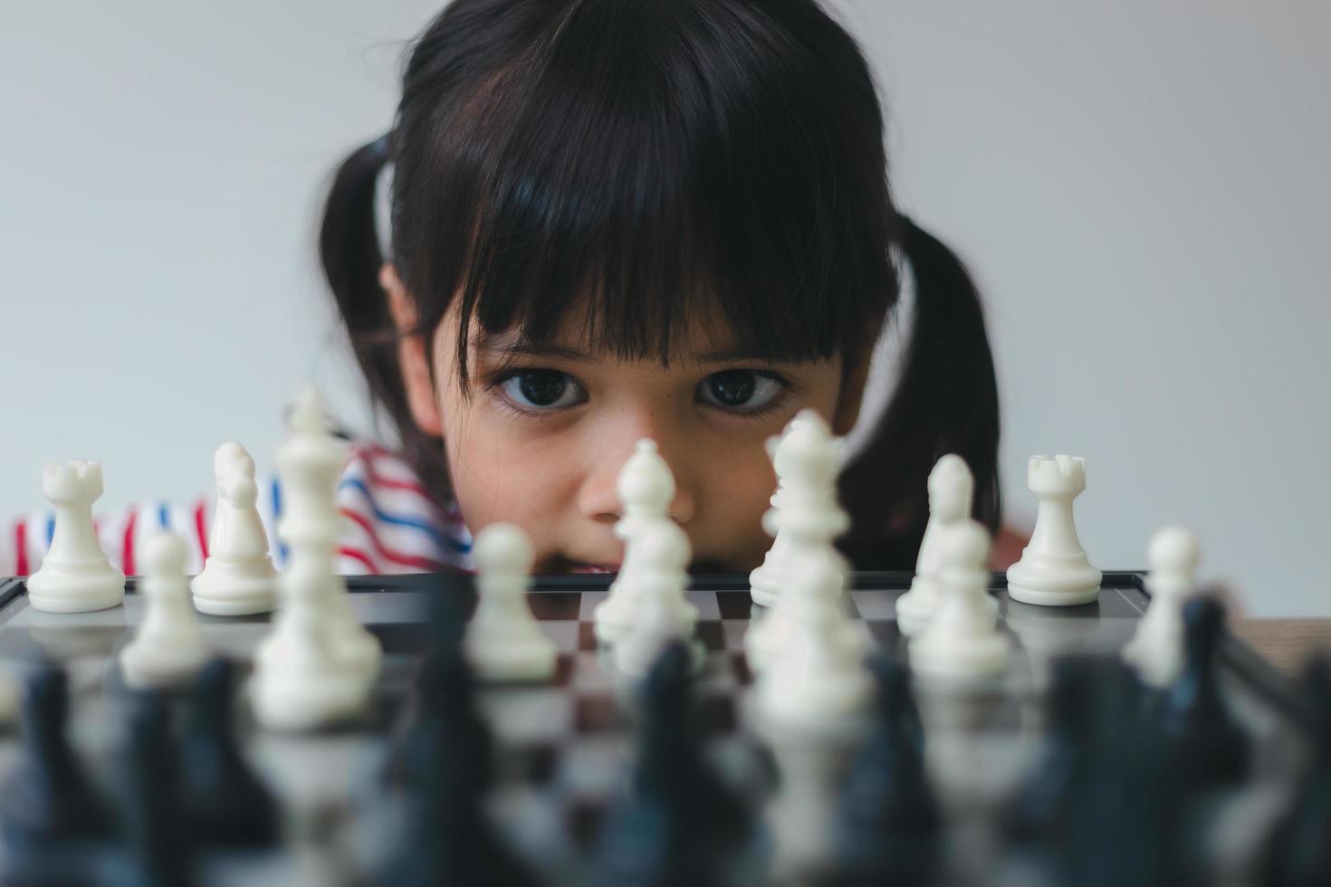 niña asiática jugando al ajedrez en casa.un juego de ajedrez foto