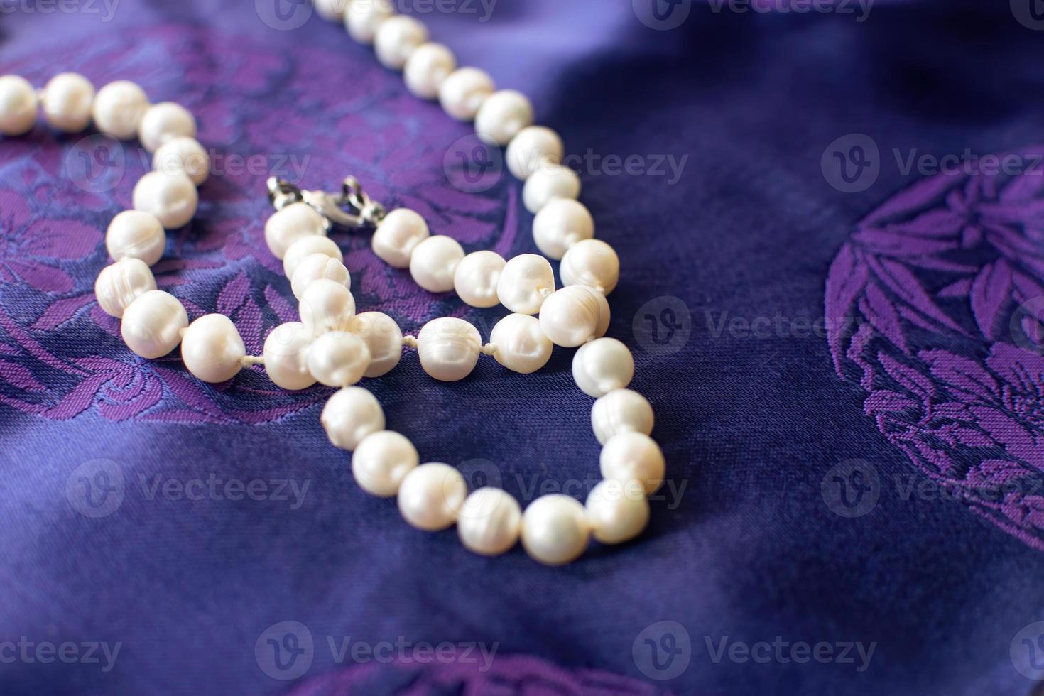 collar y pulsera de perlas de lujo sobre un fondo morado. foto