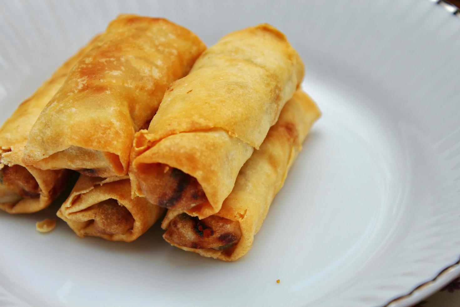 Fried spring rolls placed in a white plate, fried spring rolls are a popular Asian dish. photo