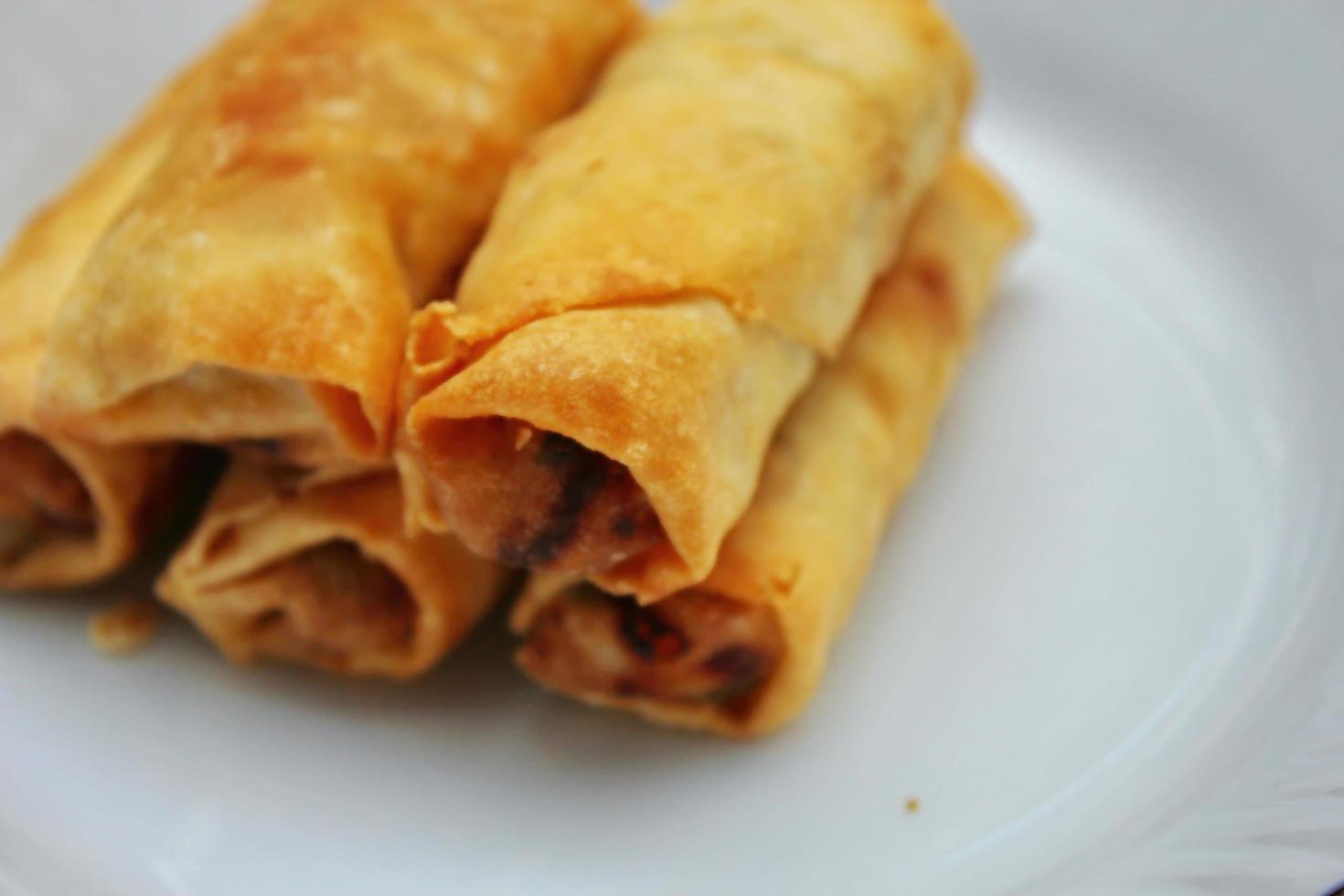 Fried spring rolls placed in a white plate, fried spring rolls are a popular Asian dish. photo