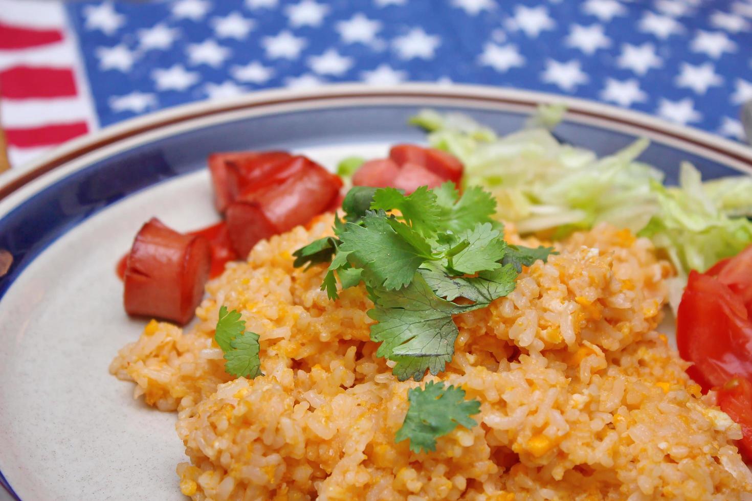 Fried rice with fried sausage served in a creamy dish with tomatoes and cucumbers. photo