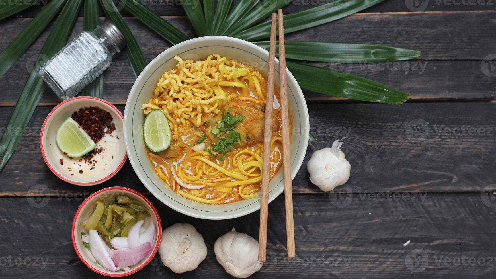 receta de khao soi, khao soi, khao soi kai, fideos tailandeses khao soi, curry de pollo con condimento servido en una mesa de madera foto