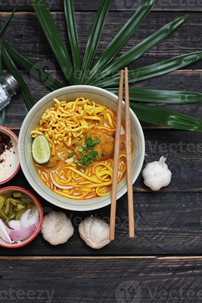 Khao Soi Recipe,Khao Soi,Khao Soi Kai, Thai Noodles Khao Soi, Chicken Curry with seasoning served on wooden table photo