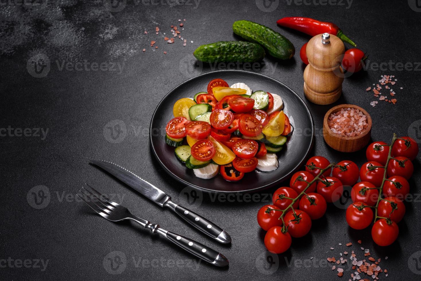 Fresh, delicious salad with cherry tomatoes, cucumbers, sweet peppers, cheese and olive oil photo