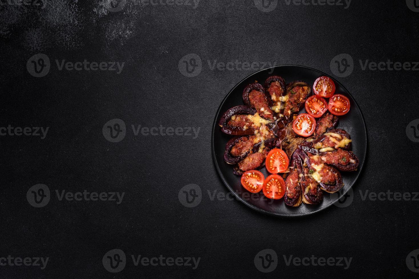 Fresh eggplant baked with minced meat, spices and herbs on a black plate photo