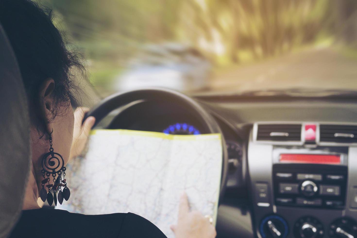 la mujer está mirando peligrosamente un mapa mientras conduce un automóvil foto