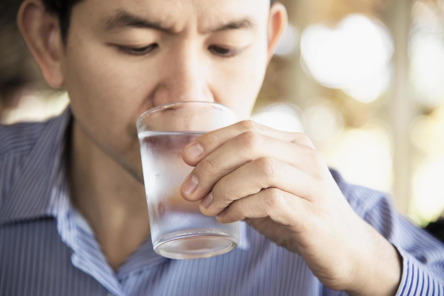 el hombre bebe agua fresca y pura en un vaso foto