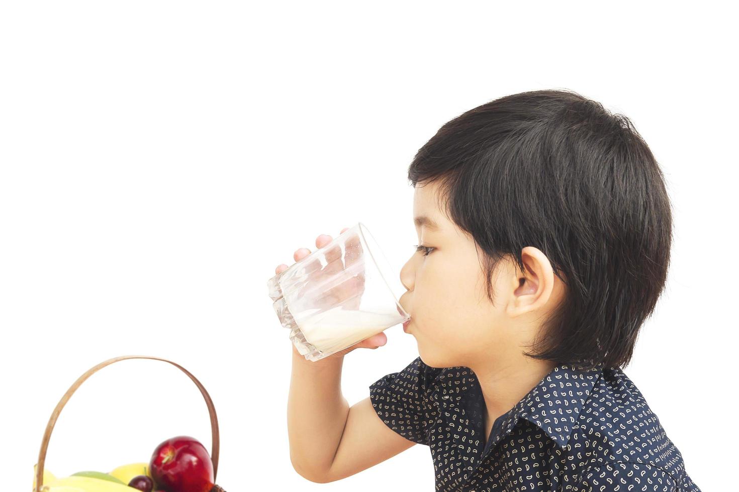 Asian boy is drinking a glass of milk isolated over white background photo