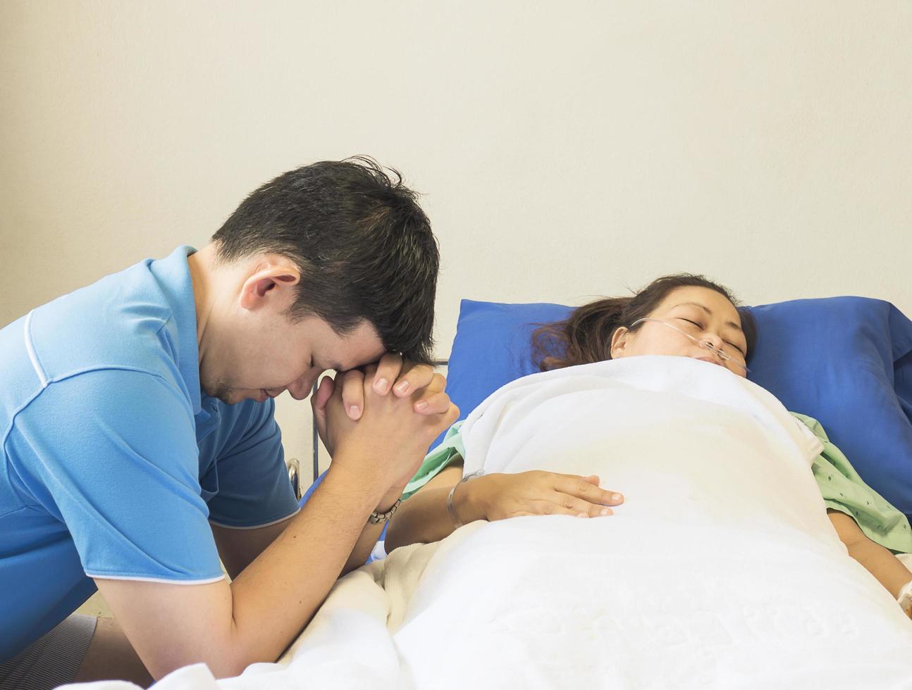 A man is praying for his beloved sick woman to get well soon in the hospital photo