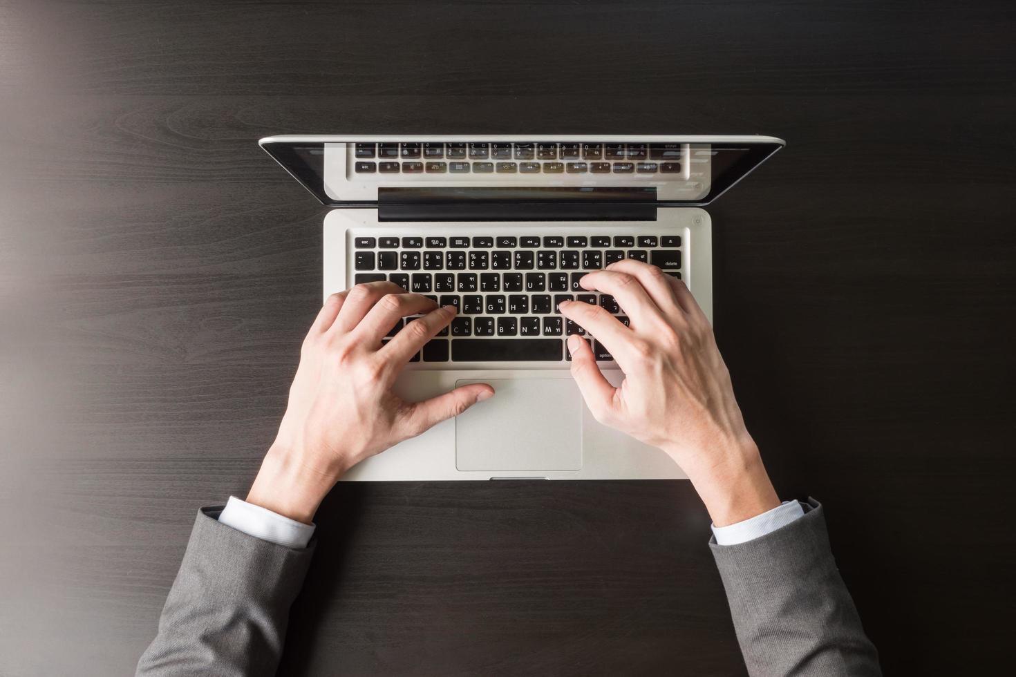 Top view of Businessman using Laptop on the black desk. photo