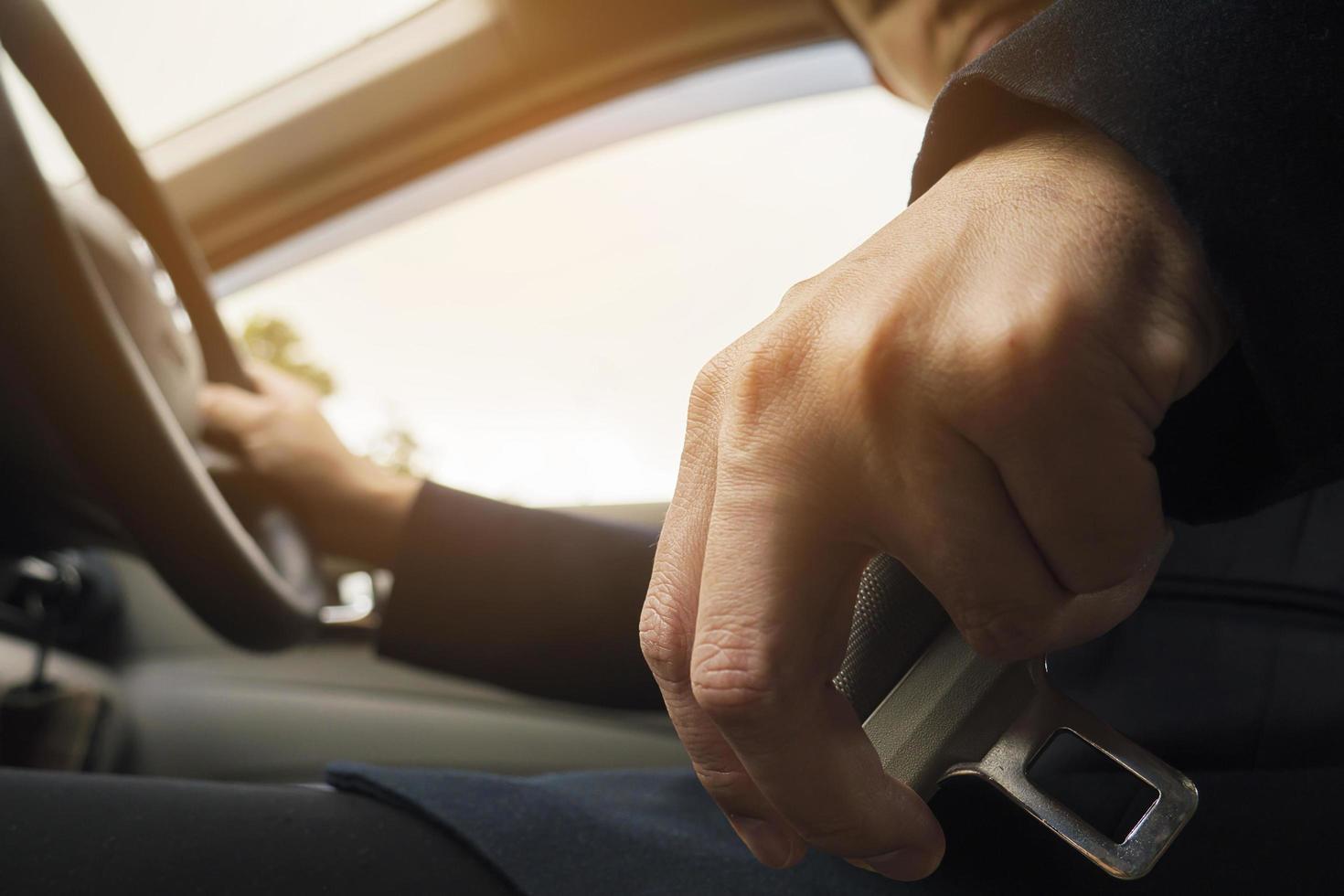 Man putting car seat belt before driving, close up at belt buckle, safe drive concept photo