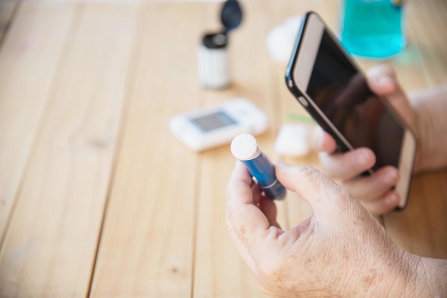 Old lady is testing blood sugar level using blood sugar test kid set - people with medical equipment concept photo