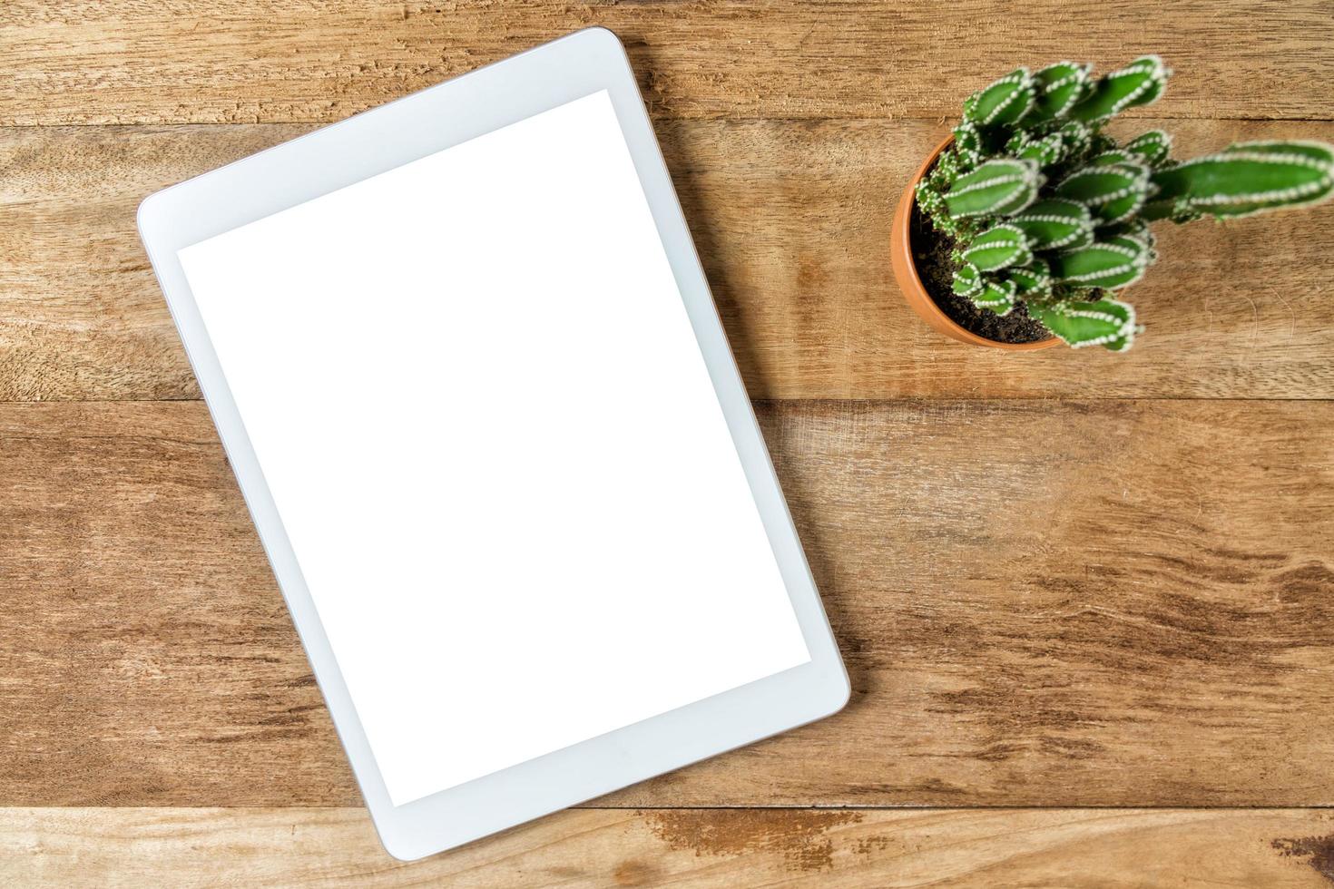 Blank modern digital tablet on a wooden desk. Top view photo