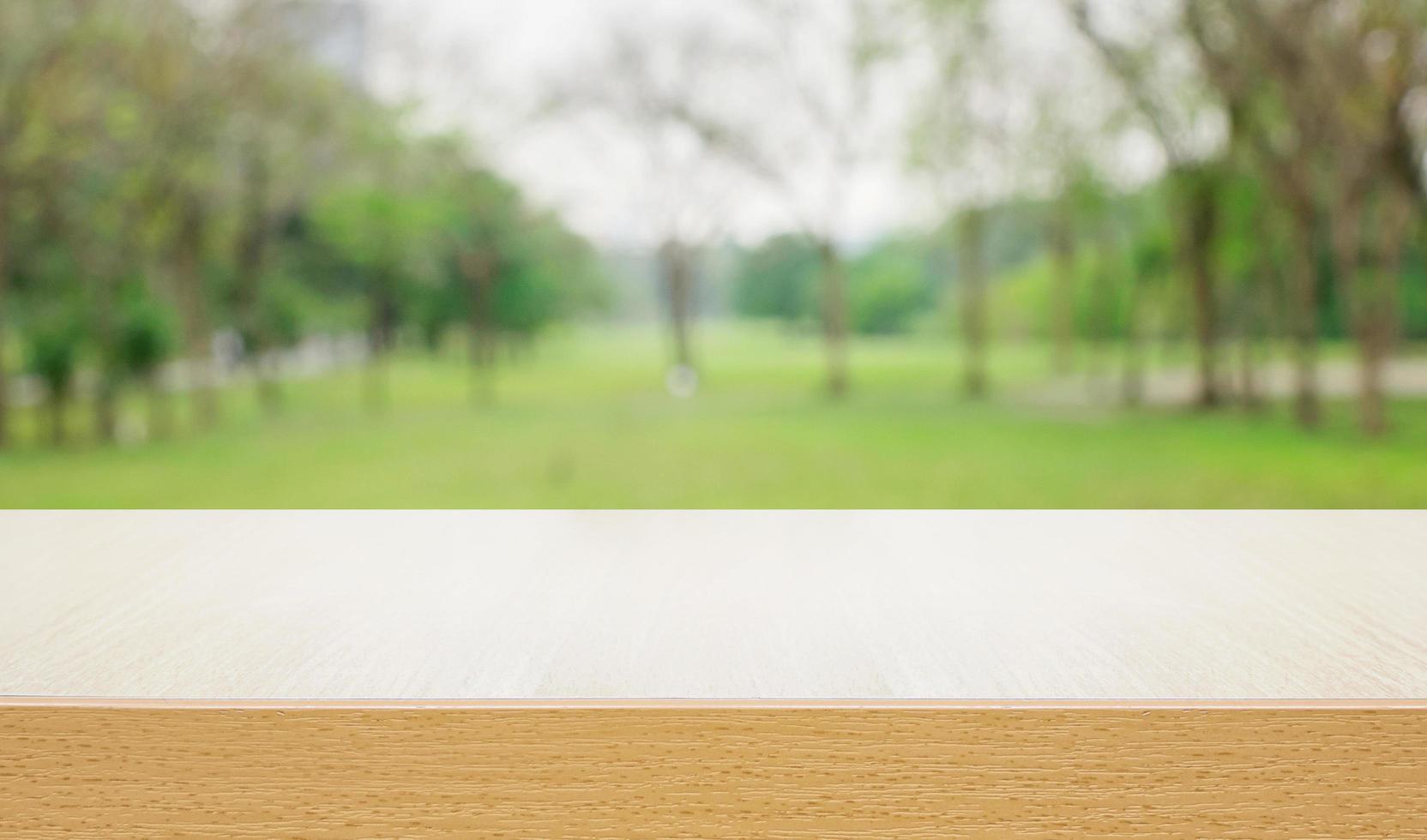 Empty wooden deck table over blurred tree with bokeh background photo