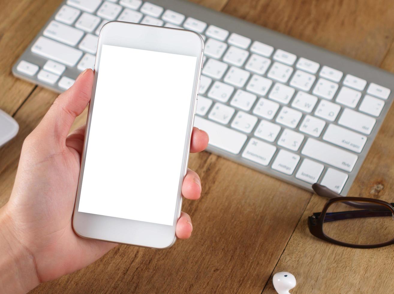 woman hand holding empty screen of smartphone on wood desk work. photo