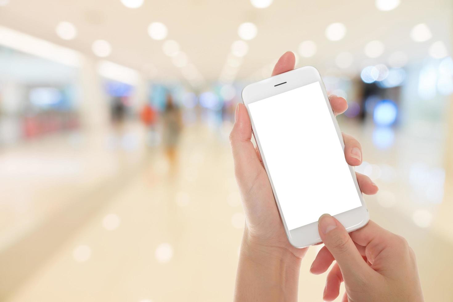 Woman hand showing smart phone with isolated screens display in a market or department store photo