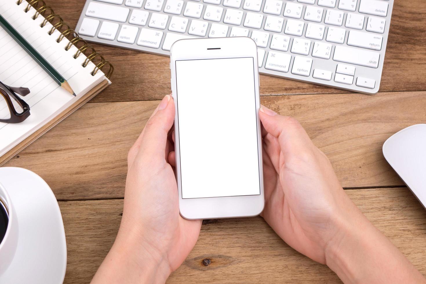 woman hands holding empty screen of smartphone on wood desk work. photo