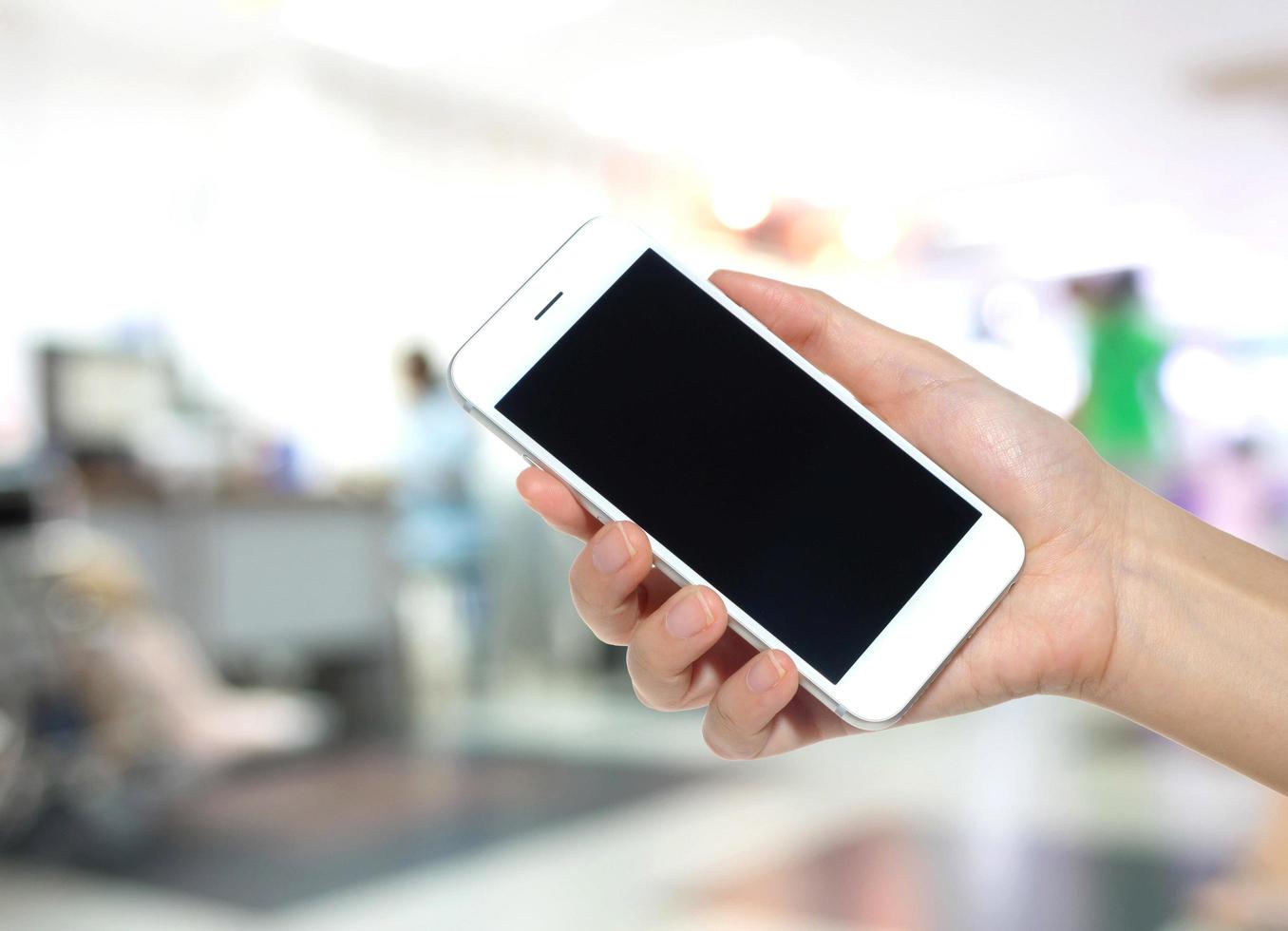 Woman hand holding empty screen of smartphone with Abstract blur hospital background photo