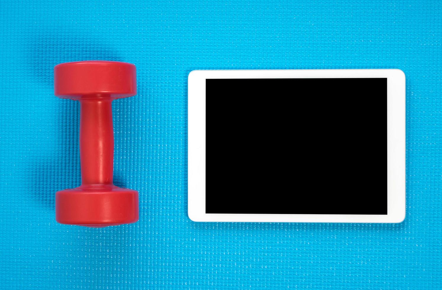 Blue yoga mat,dumbbell with tablet photo