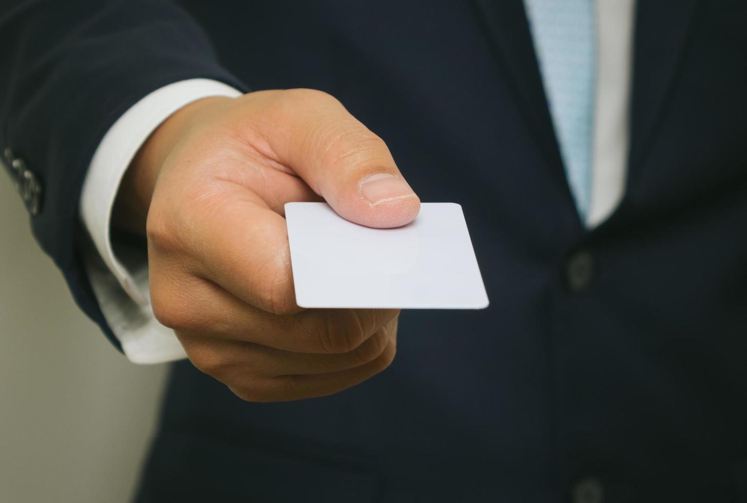 Business man handing a blank business card over white background photo