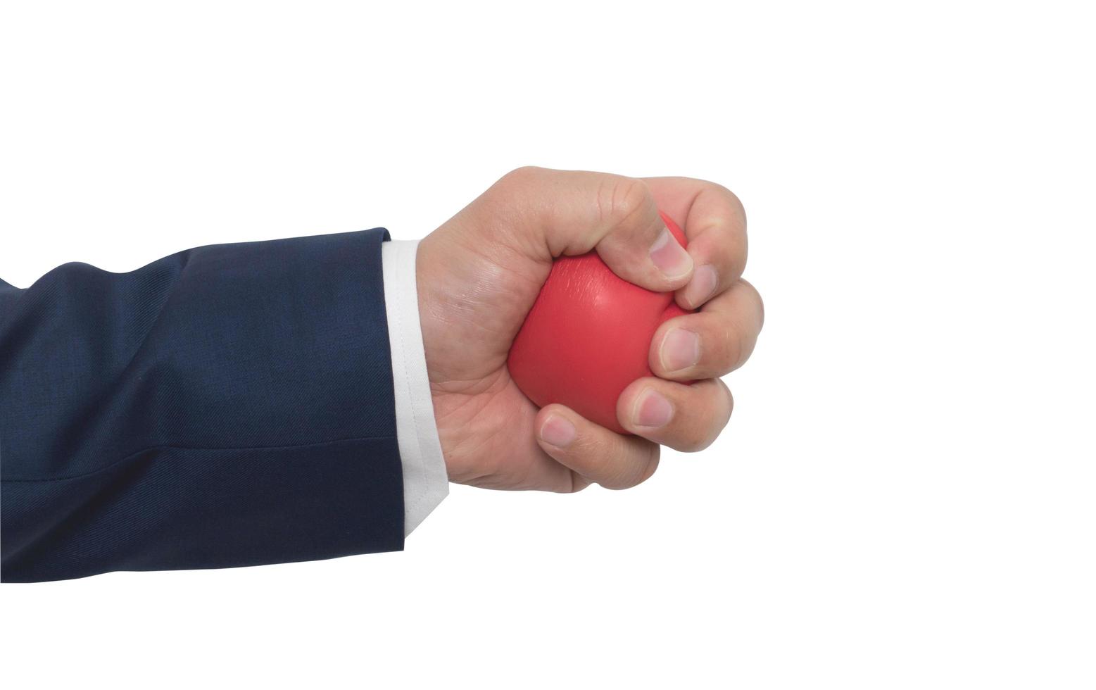 una mano de hombre apretando una pelota antiestrés sobre fondo blanco foto