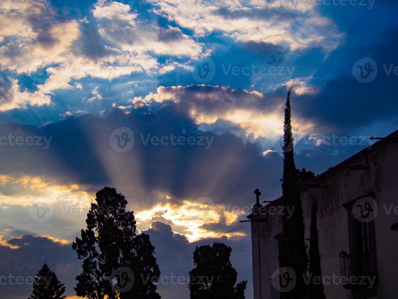 Sunlight peeking through the clouds near a crucifix signaling a change photo