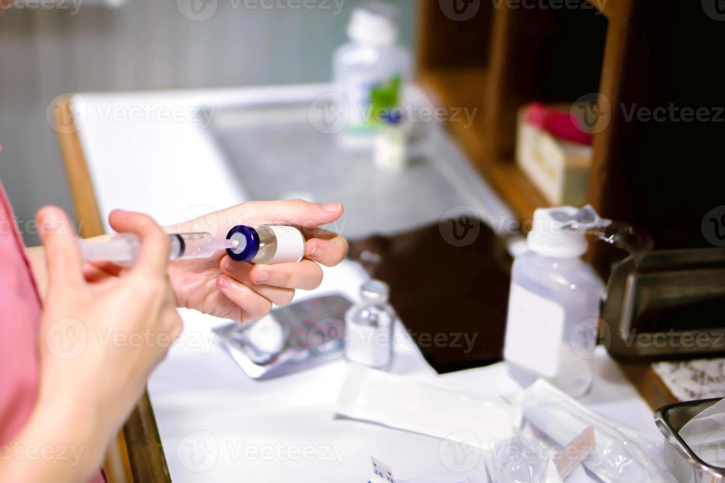 una imagen de las manos de la enfermera preparando una vacuna inyectable para el paciente. foto