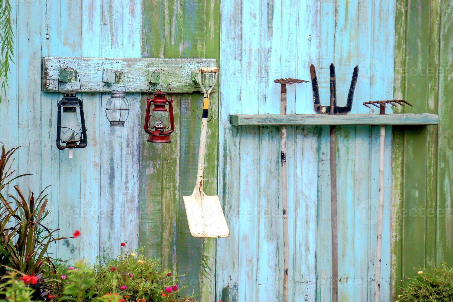 Gardening equipment hanging on blue color wooden wall. photo