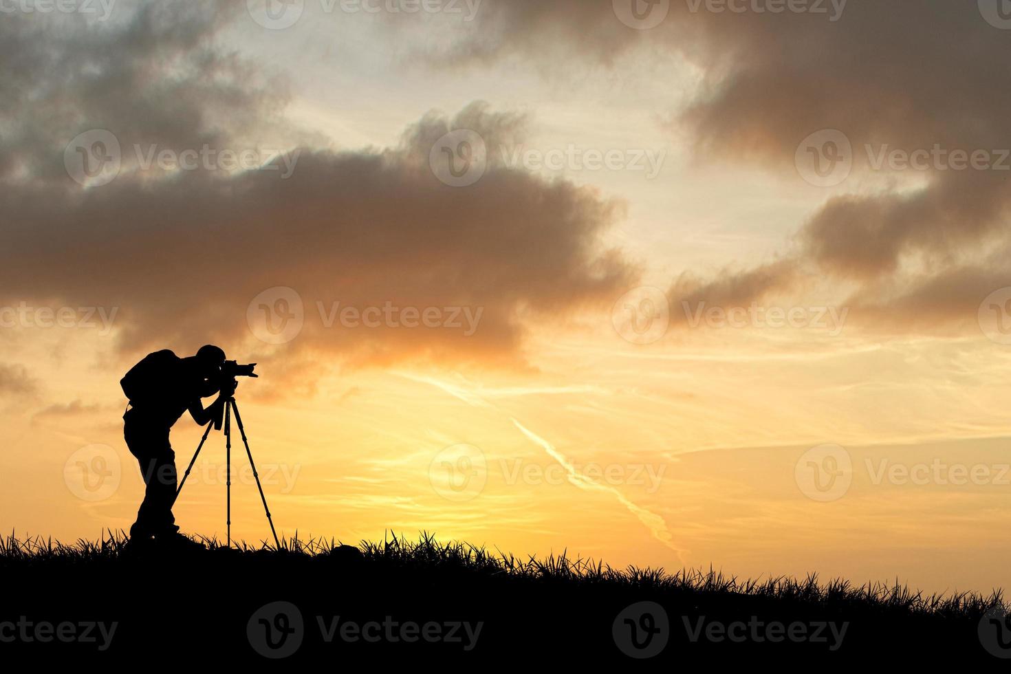 A professional photographer's silhouette is focused on shooting in a beautiful meadow. photo