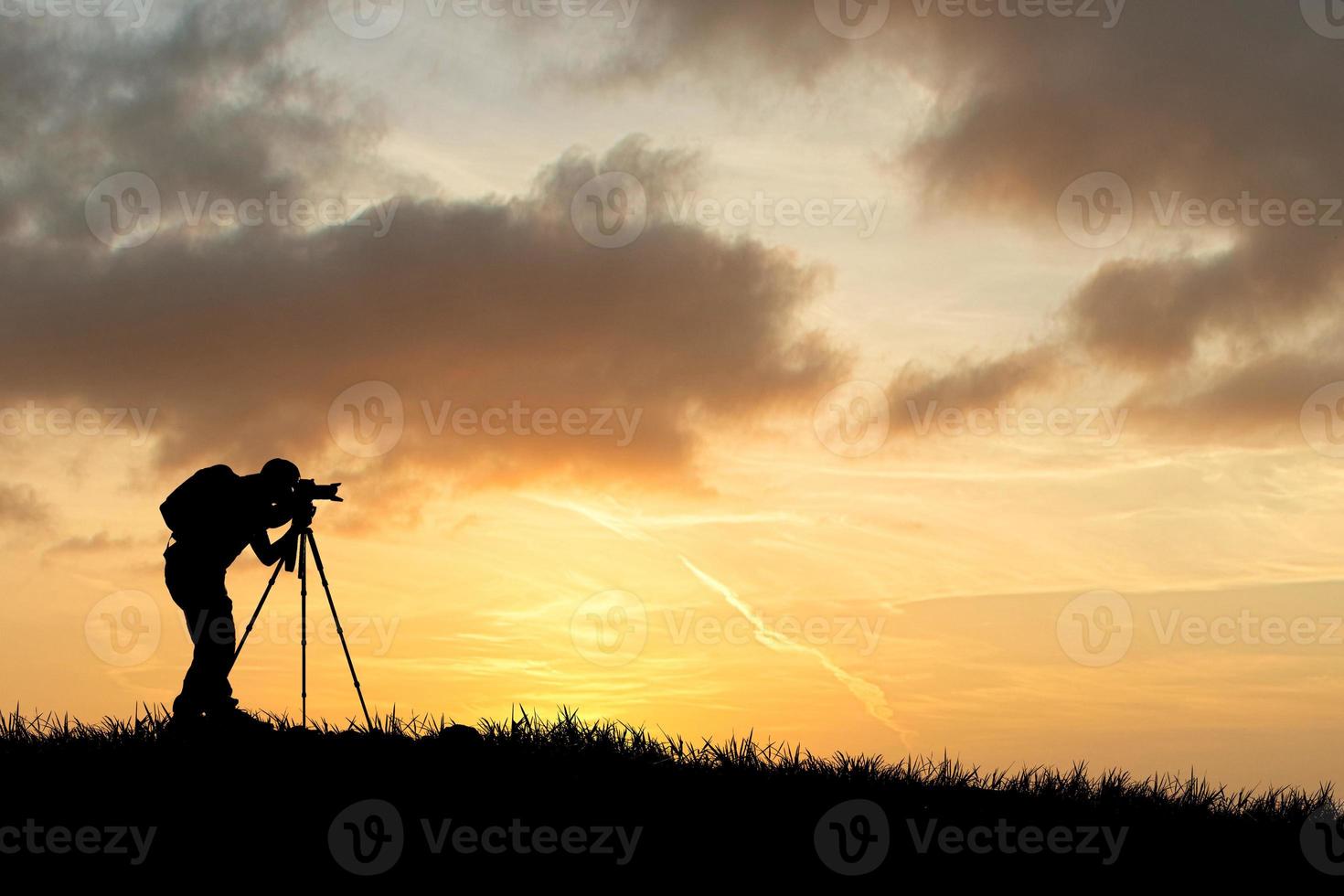 la silueta de un fotógrafo profesional se centra en disparar en un hermoso prado. foto