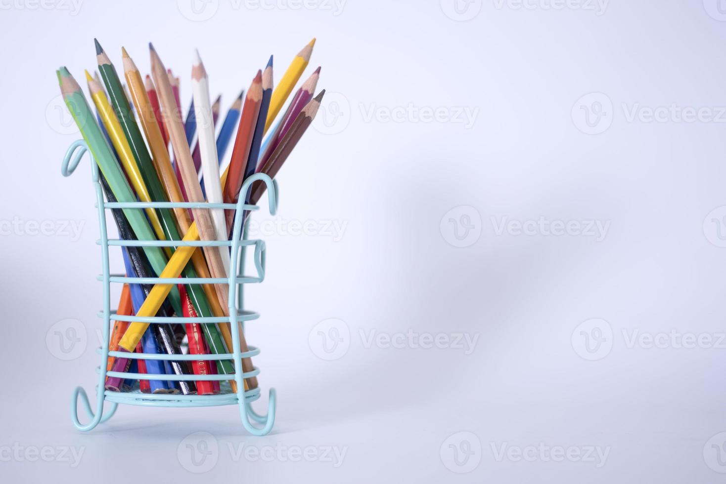 Lots of colorful pencils for drawing in a green glass on a gray background, copy space photo