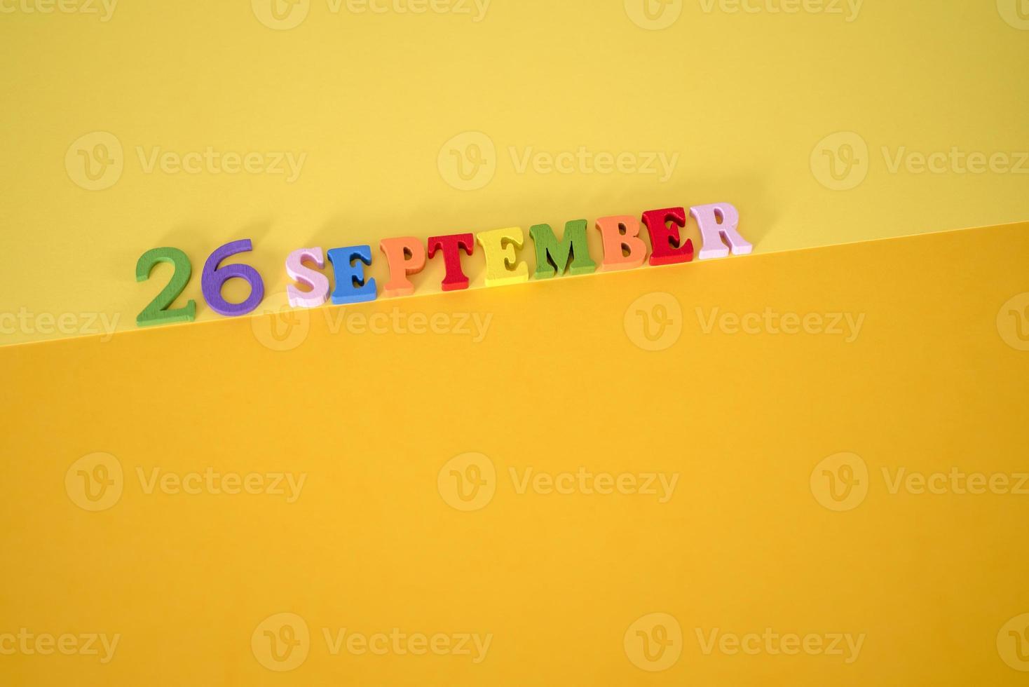 September 23 on a yellow and paper background with wooden letters and numbers in different colors. photo