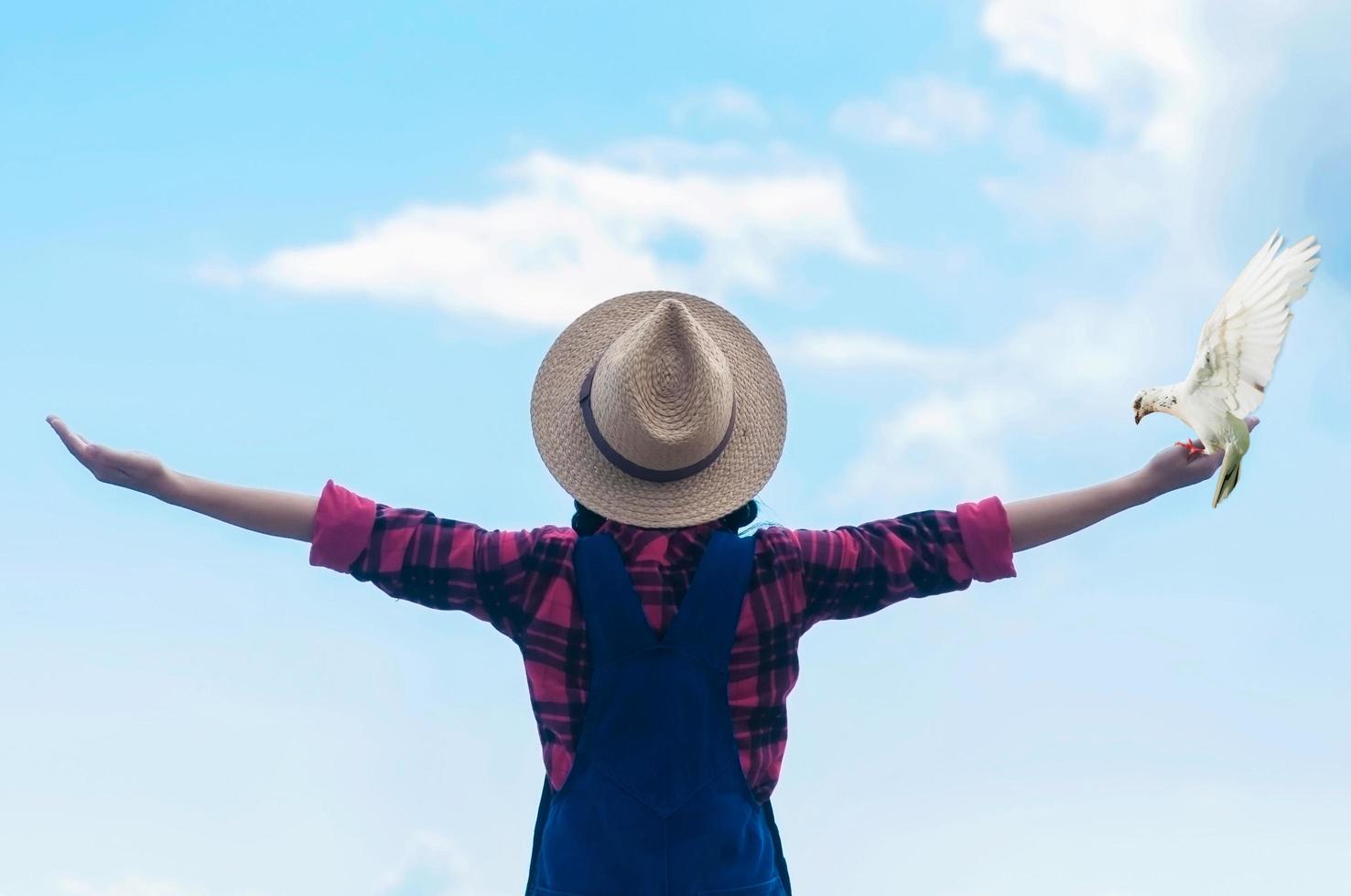 people and animal freedom concept - lady raising out her hand with bird white dove showing freedom feeling emotion with bright blue sky and cloud backgound photo