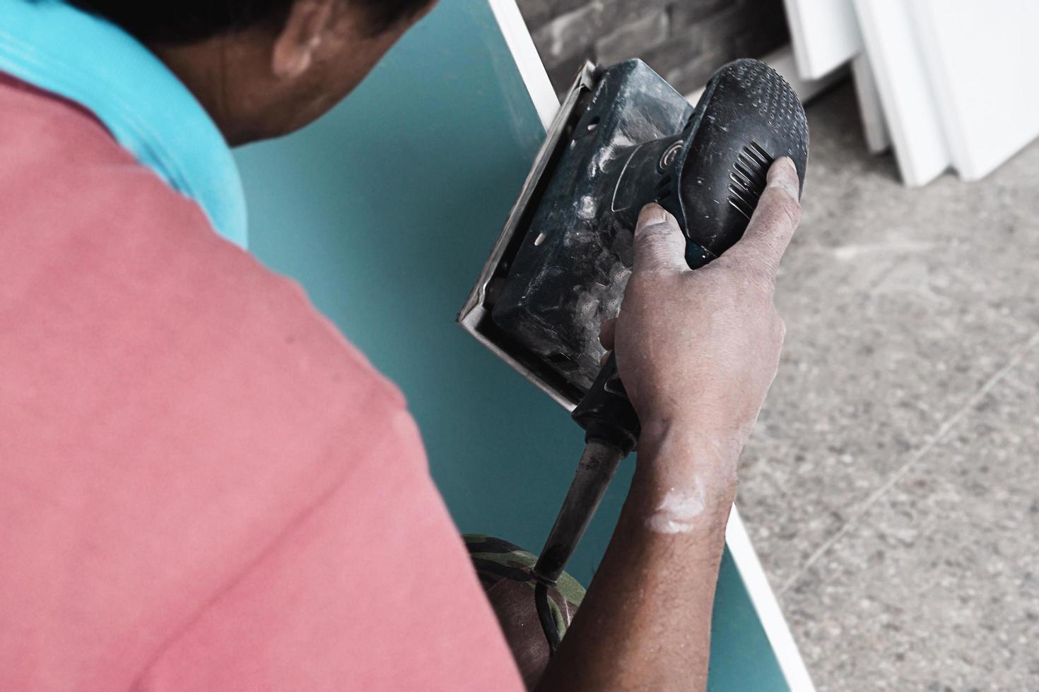 el pintor está trabajando en el proceso de pintura de muebles usando una máquina de limpieza que hace que el color de la superficie sea suave y limpio - carpintero que trabaja con el concepto de herramienta manual foto