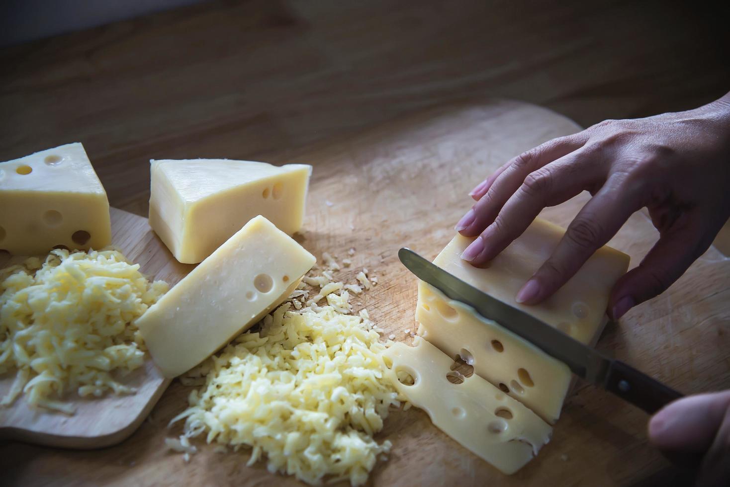 Woman preparing cheese for cook using cheese grater in the kitchen - people making food with cheese concept photo