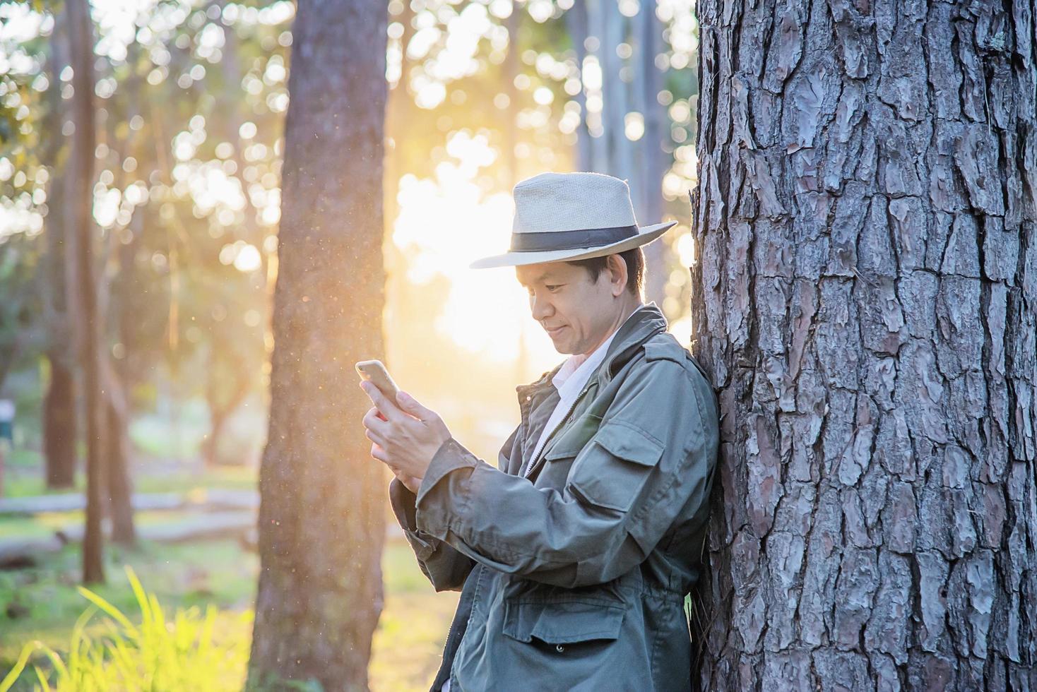 Asian man with mobile phone in forest tree nature - people in spring nature and technology concept photo