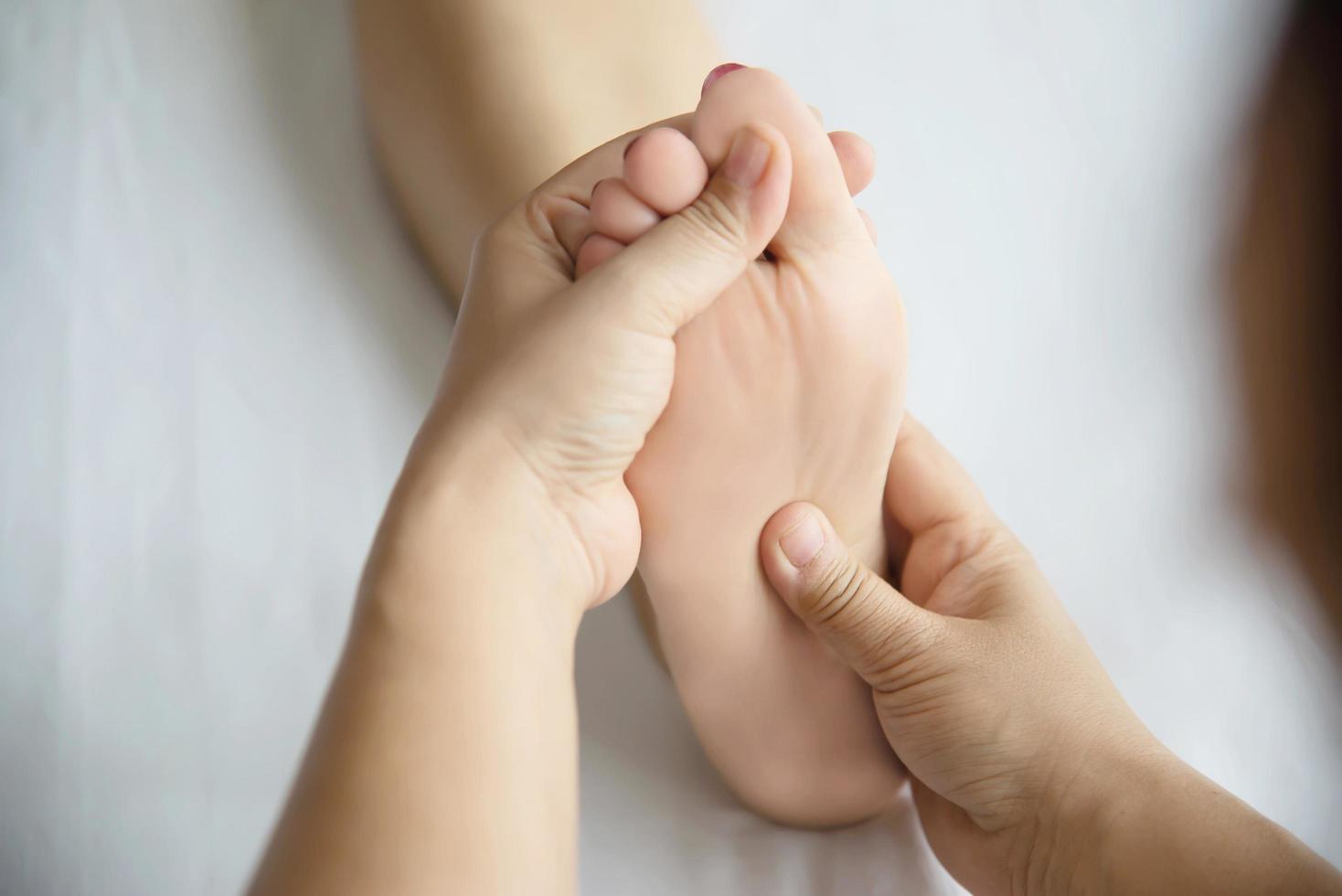 Woman receiving foot massage service from masseuse close up at hand and foot - relax in foot massage therapy service concept photo