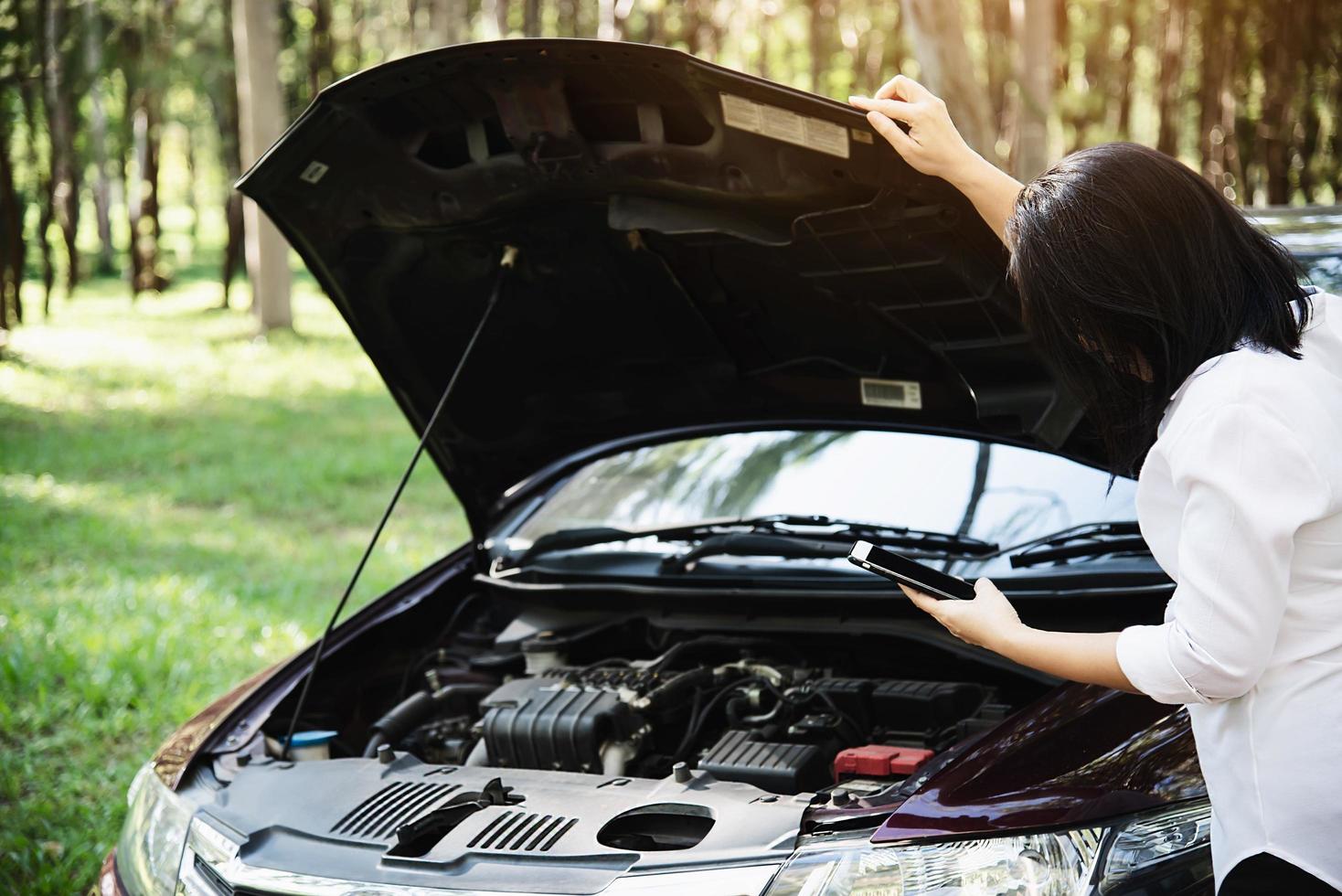 Asian woman calling repairman or insurance staff to fix a car engine problem on a local road - people with car problem transportation concept photo