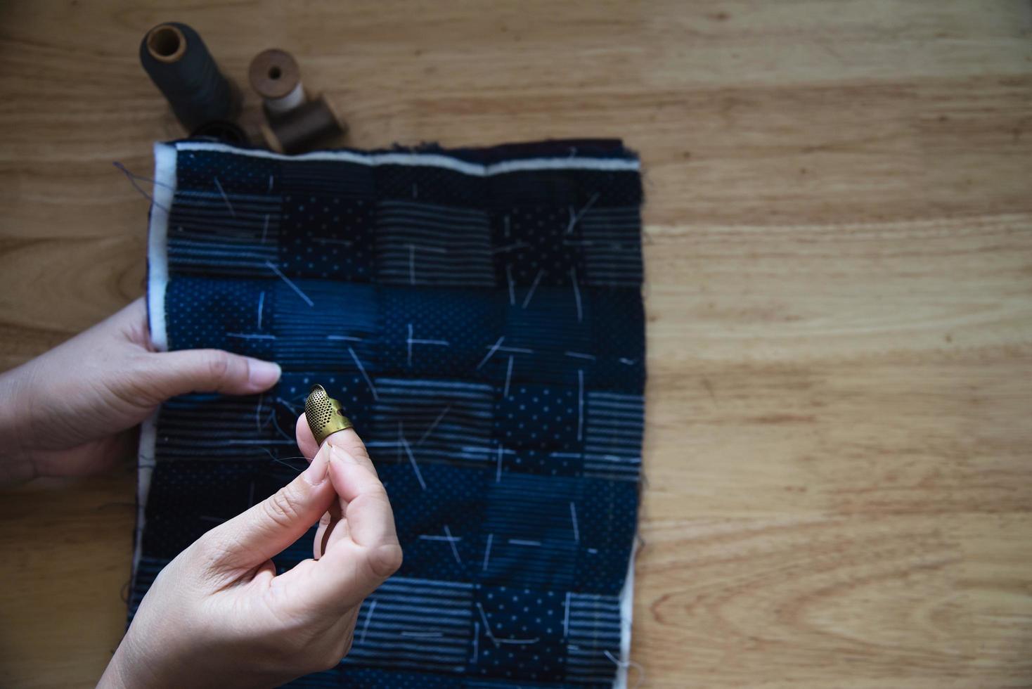 mujer vintage cosiendo tela a mano con bordados sobre fondo de mesa de madera - gente y concepto de tareas domésticas hechas a mano foto