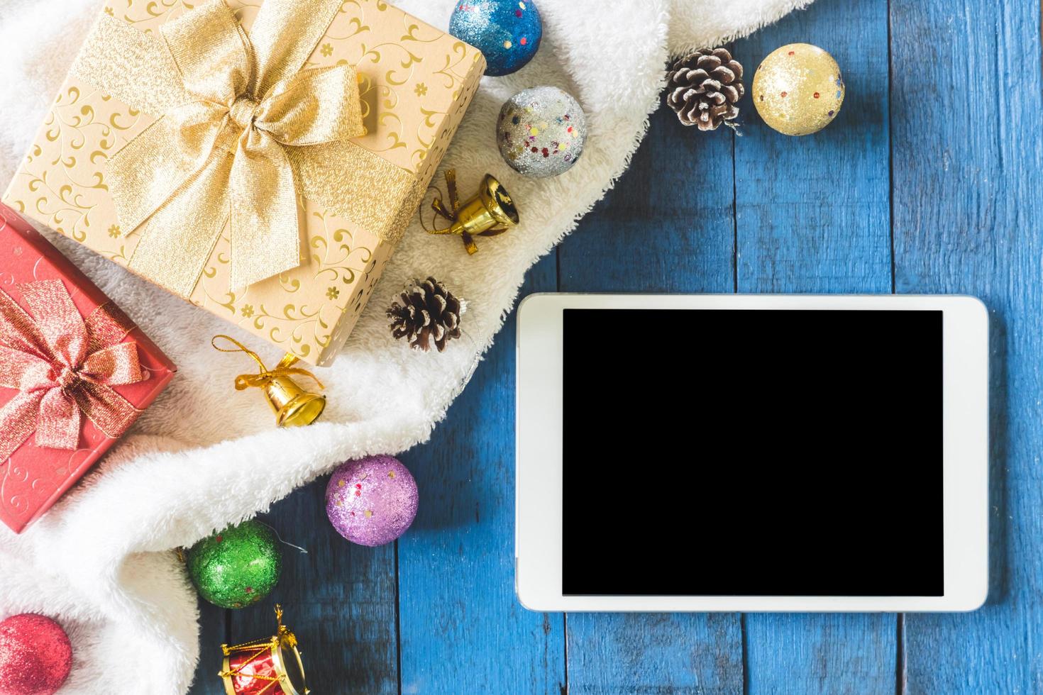 Top view of Gift boxes with Christmas decoration and Tablet on wooden table background photo